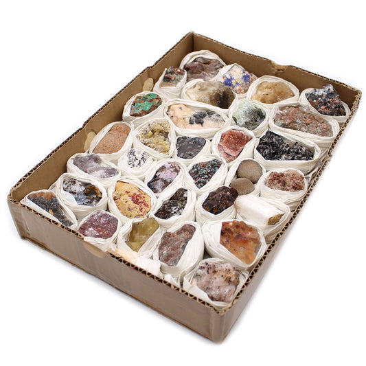 Box of assorted small rocks and minerals in white bags on a white background
