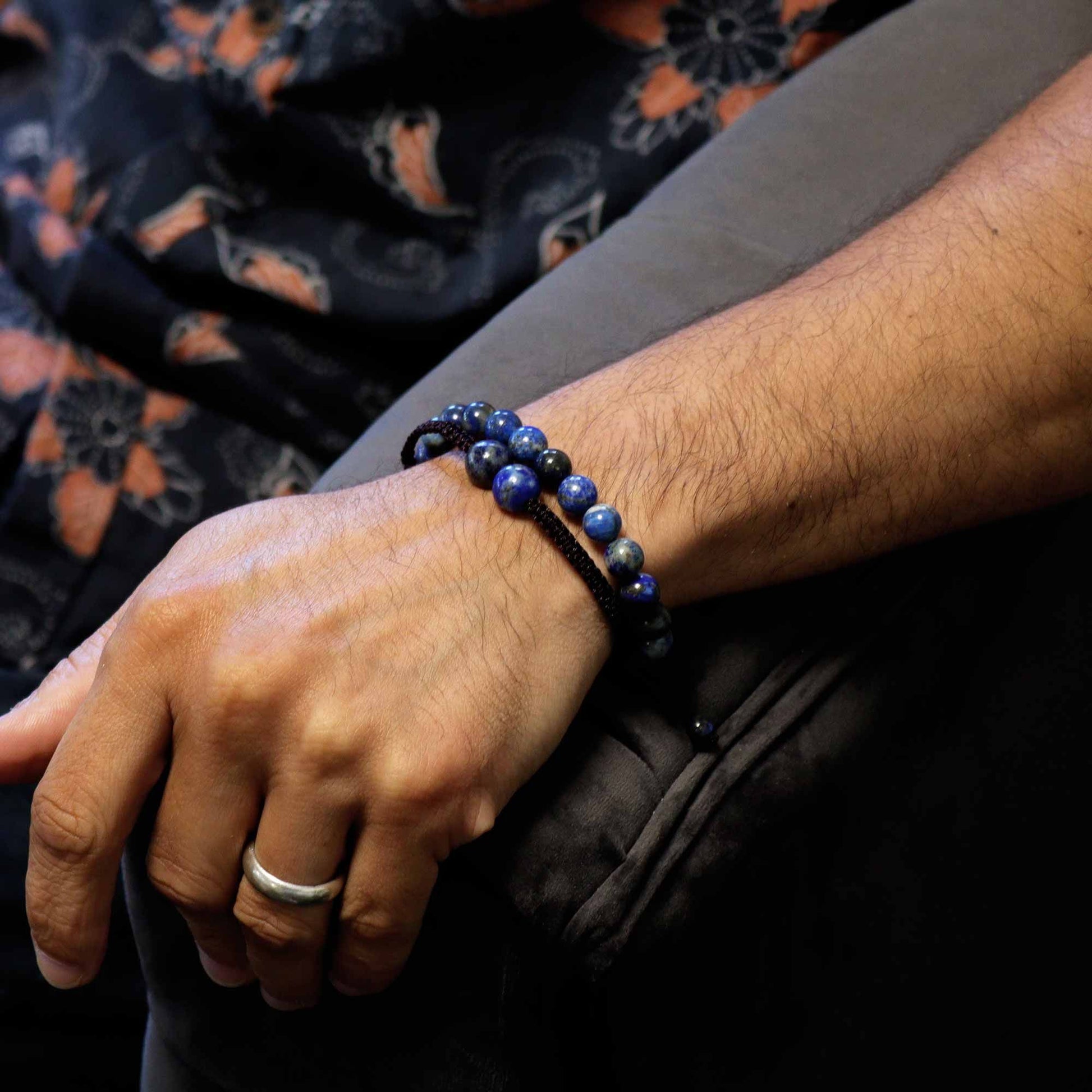 Person wearing a black beaded bracelet on a dark background