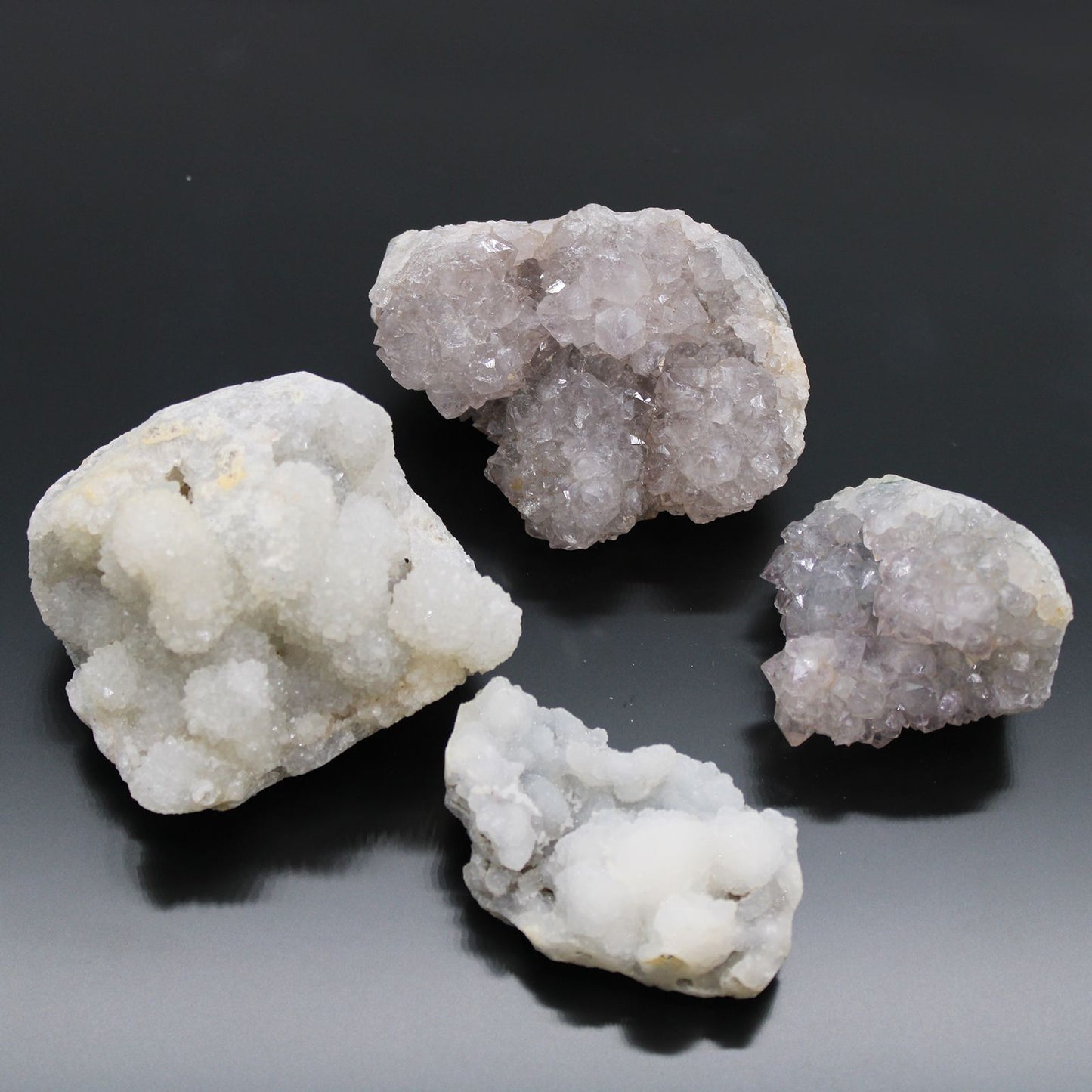Four crystal rocks on a reflective black surface