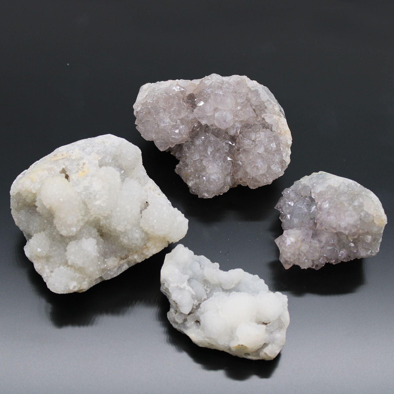 Four crystal rocks on a reflective black surface