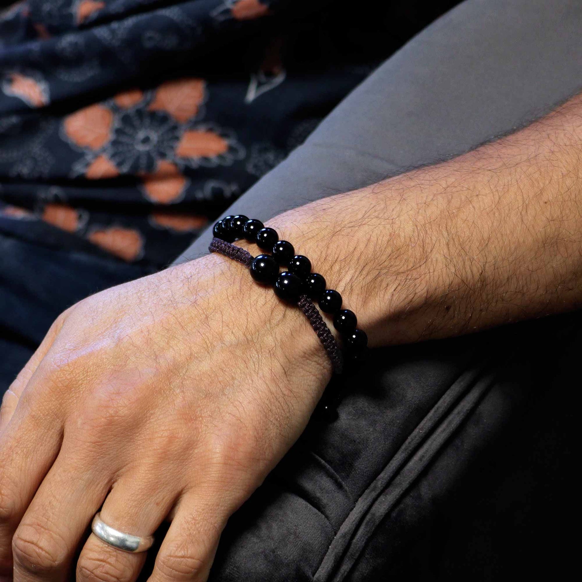 Hand wearing a black beaded bracelet with a blurred background
