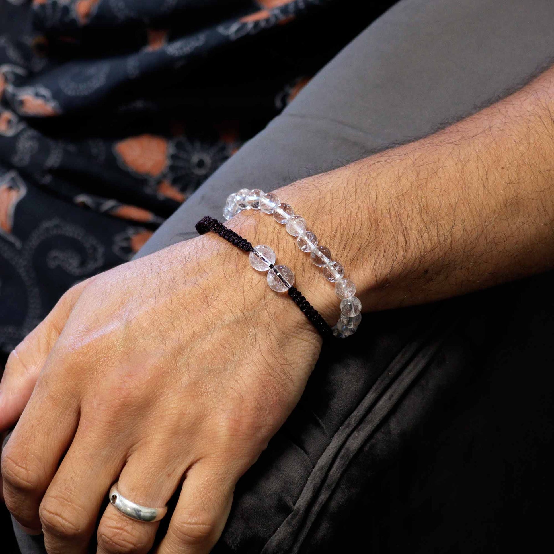 Person wearing two bracelets on a dark background